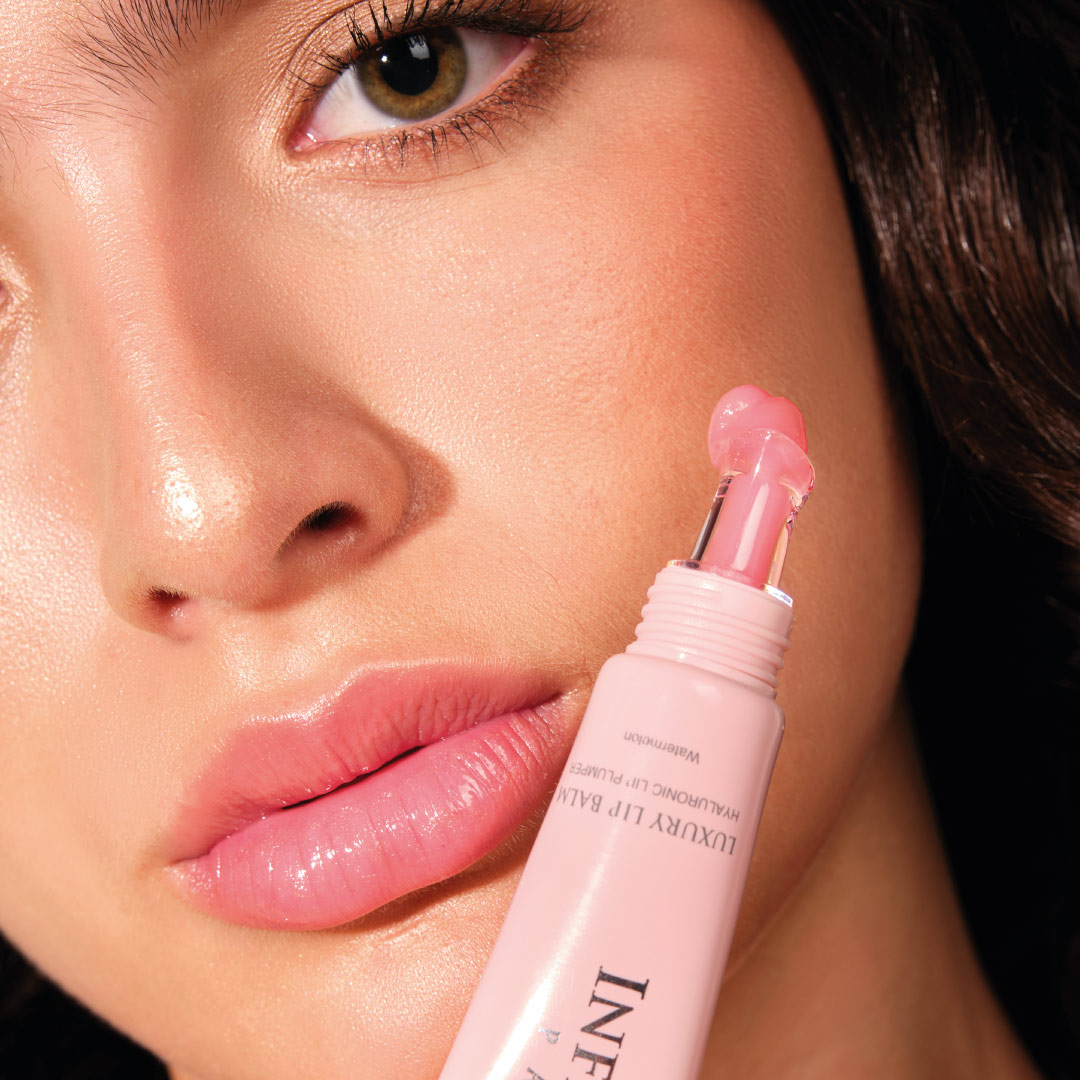 mujer modelo latina sosteniendo en la mano un luxury lip balm de infinitek paris, lindos ojos, voluminizador de labios
