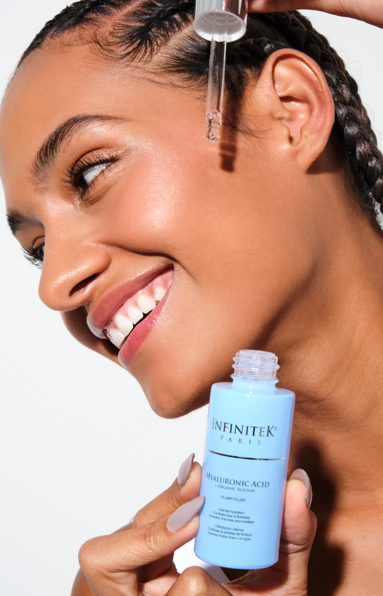 mujer modelo afro sosteniendo frasco de acido hialuronico de infinitek paris, aplicandoselo en la cara o el rostro para cuidado facial.
